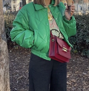Women's green quilted faux leather puffer jacket with snap buttons in a street style look