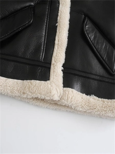 Detailed close-up of a black faux leather jacket with fleece trim and flap pockets