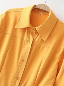 Close-up of bright yellow shirt dress collar featuring sharp lapels and tonal buttons