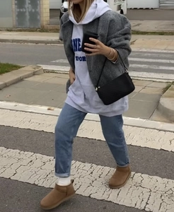 Street style view of dark grey tweed jacket paired with white hoodie and light blue jeans