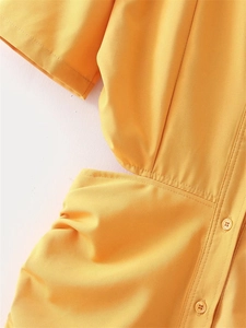 Detail view of yellow dress featuring short sleeves, front buttons, and waist cut-out design
