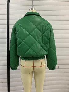 Detail view of green faux leather quilted jacket featuring large diamond stitching and ribbed cuffs