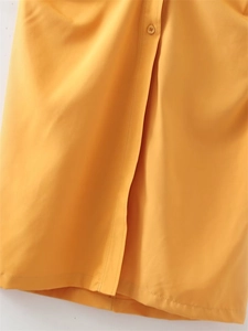 Detailed close-up of bright yellow dress featuring resin buttons and fine stitching