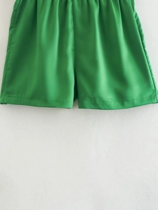 Detailed view of green satin high waist shorts with elastic waistband and glossy fabric texture