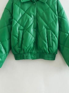 Detail view of vibrant green quilted PU leather jacket with snap buttons and elastic hem