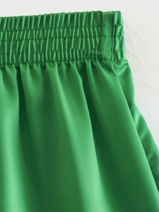Detail of bright green high-waisted elastic smocked waistband on lightweight shorts