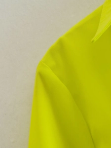 Gros plan des coutures de qualité sur le col et l'épaule de la chemise vert néon