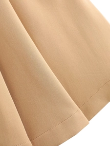 Makroaufnahme von khakifarbenem Twill-Stoff und präzisen Bodennähten an einem Faltenrock