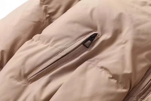 Macro detail of high-quality black metal zipper on warm beige quilted winter jacket