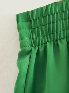 Detail of emerald green high-waisted shorts with smocked elastic waistband and subtle pleats