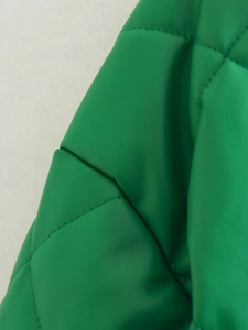 Macro shot of green faux leather fabric with classic diamond quilting and fine stitching