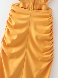 Detail of ruched fabric and waist cut-out on a ginger yellow bodycon dress