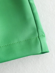 Macro view of green high waist shorts showing detailed double-stitched hem and fabric texture