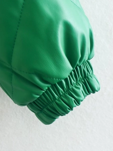 Detailed close-up of quilted green faux leather jacket cuff with elastic ribbed design