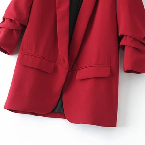 Detail of red blazer with ruched sleeves, notched lapels and flap pockets