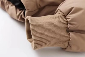 Detail of khaki puffer jacket showing windproof fabric and ribbed elastic cuffs