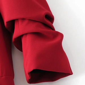 Close-up of layered pleated cuffs on a red blazer with textured crepe fabric detail