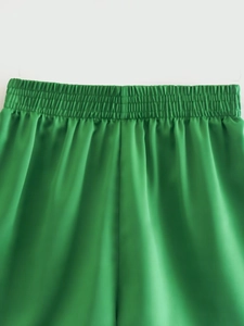 Detail of high waist green satin shorts with elasticated smocked waistband texture