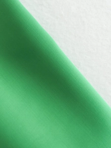 Macro close-up of vibrant green twill fabric texture and fine diagonal weave details