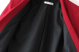Close-up of red casual blazer collar showing black silk lining and size label details