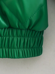 Detail view of green faux leather jacket featuring quilted patterns and elastic hem