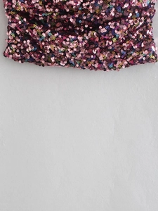 Close-up of vibrant pink and purple sequins on y2k style strapless top fabric detail