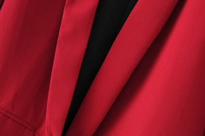 Close-up of vibrant red blazer lapel featuring high-quality woven texture and black lining