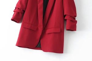 Detail of red blazer showing notched lapels, single-button closure and ruched sleeves