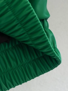 Detail of green faux leather puffer jacket featuring elastic ribbed cuffs and hem texture