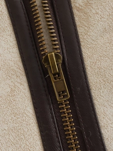 Detailed close-up of high-quality metal zipper and suede fabric on autumn vest jacket