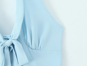 Detail of light blue halter dress featuring a large bow tie and delicate pleats
