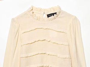 Detail of ruffle high neck and layered pleats on beige slim-fit long sleeve top