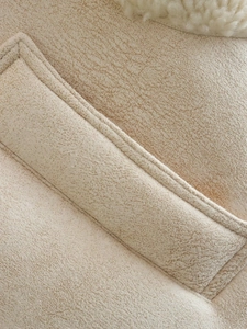 Close-up of beige suede fabric with soft faux shearling lining and quilted stitching details