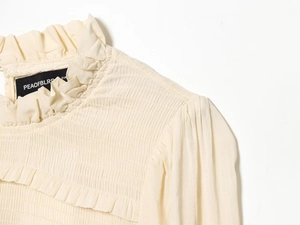 Detail of smocked texture and ruffled collar on slim fit beige long sleeve t-shirt