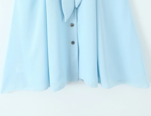 Detail of light blue dress showing neck tie-bow and buttons with mica texture