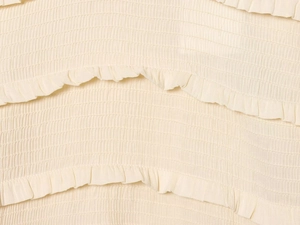Close-up of cream white smocking fabric with delicate ruffles and pleated texture