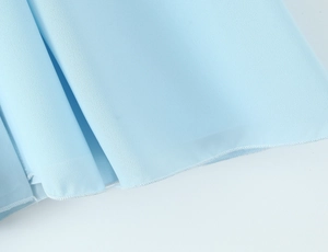 Detailed close-up of light blue dress hemline with professional overlock stitching craftsmanship