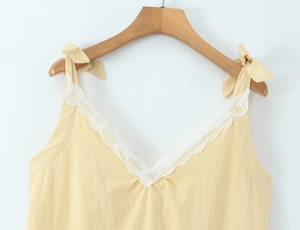 Detail of V-neckline with white floral lace trim and yellow bow shoulder straps