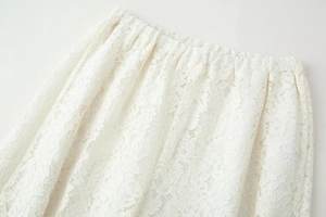 Vista detallada de la textura de encaje blanco y la cintura elástica del pantalón