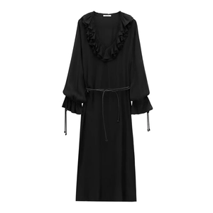 Détail de robe noire à col en V avec volants, poignets à cordon et ceinture fine nouée