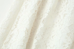 Vista macro detallada del encaje blanco bordado con un elegante diseño calado