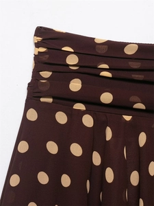 Detail of dark brown polka dot fabric featuring elegant horizontal pleated textures