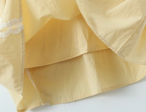 Detail of warm yellow dress hem featuring delicate white lace trim and smooth lining