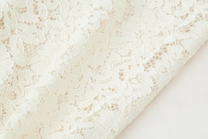 Detalle de tela de encaje blanco con elegantes bordados florales y calados delicados