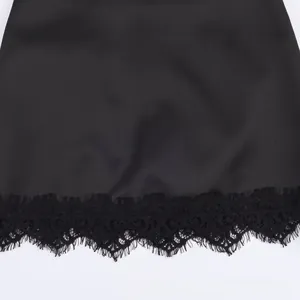 Detailed close-up of the delicate black eyelash lace trim on a silky high-waist skirt hem