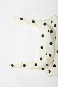 Detail showing metal snap buttons on cream polka dot bodysuit fabric texture
