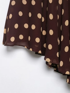 Detail of dark brown chiffon fabric with large beige polka dots and smooth hemline