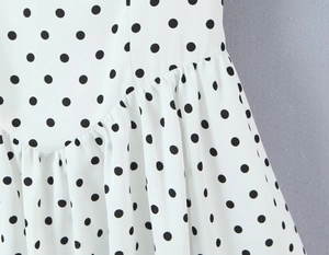 Detail von weißem Kleid mit schwarzen Punkten und asymmetrischem Rüschendesign