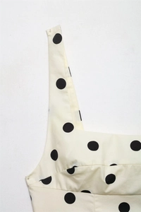 Detailed macro view of square neckline and black polka dot pattern on beige fabric