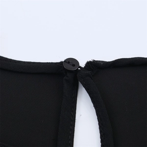 Détail de l'encolure de robe noire avec fermeture à bouton et découpe en forme de goutte